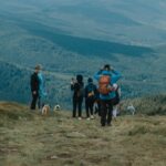 Trekking boots stepping on mossy rock overlooking tea plantation trail during Munnar Hills Trekking.