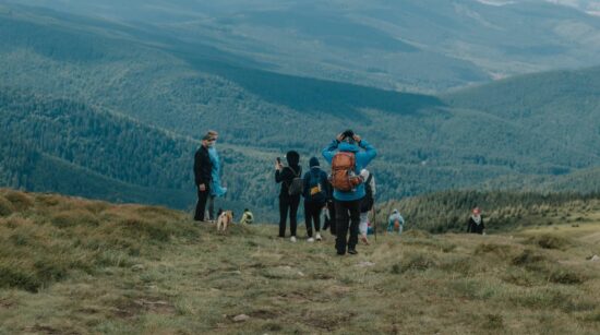 Trekking boots stepping on mossy rock overlooking tea plantation trail during Munnar Hills Trekking.
